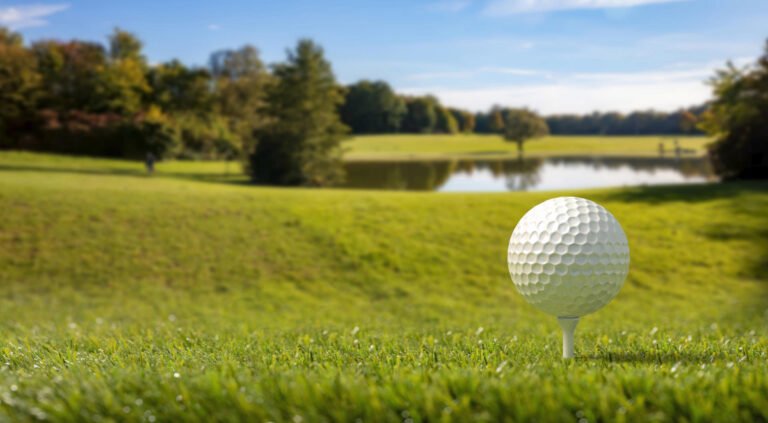 Golf ball on green looking toward a lake