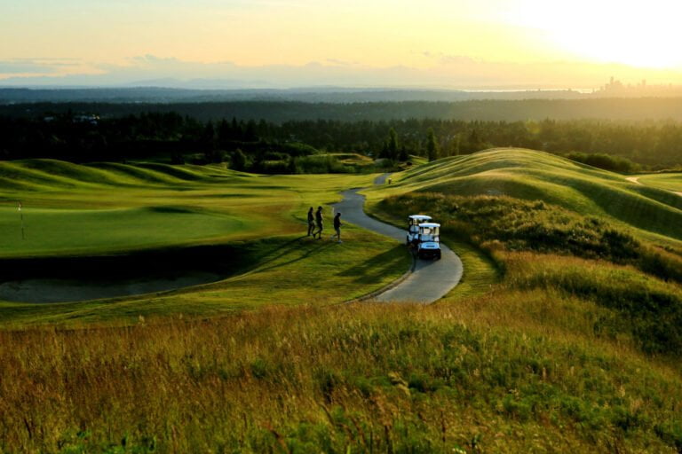 Golfers walking to their buggies at sunset